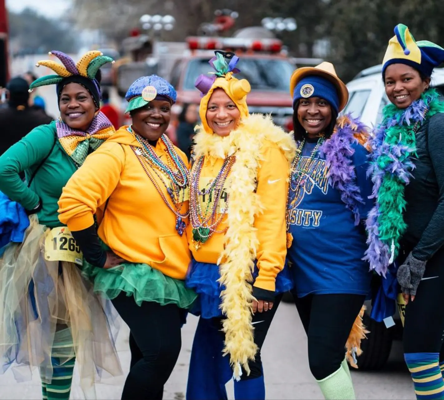 Five runners in jester hats, tutus, and feather boas